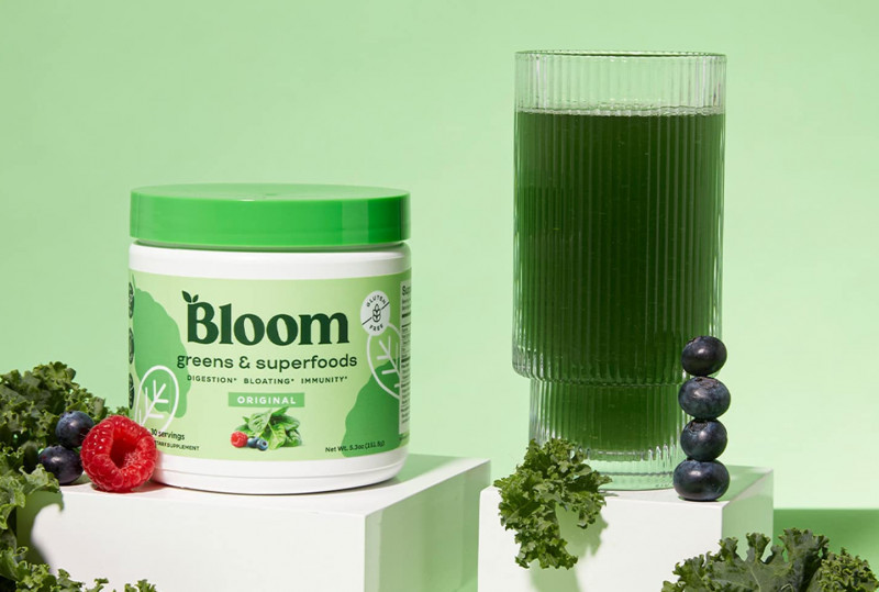 Imagen de un producto de Bloom Greens & Superfoods con un vaso sobre fondo verde